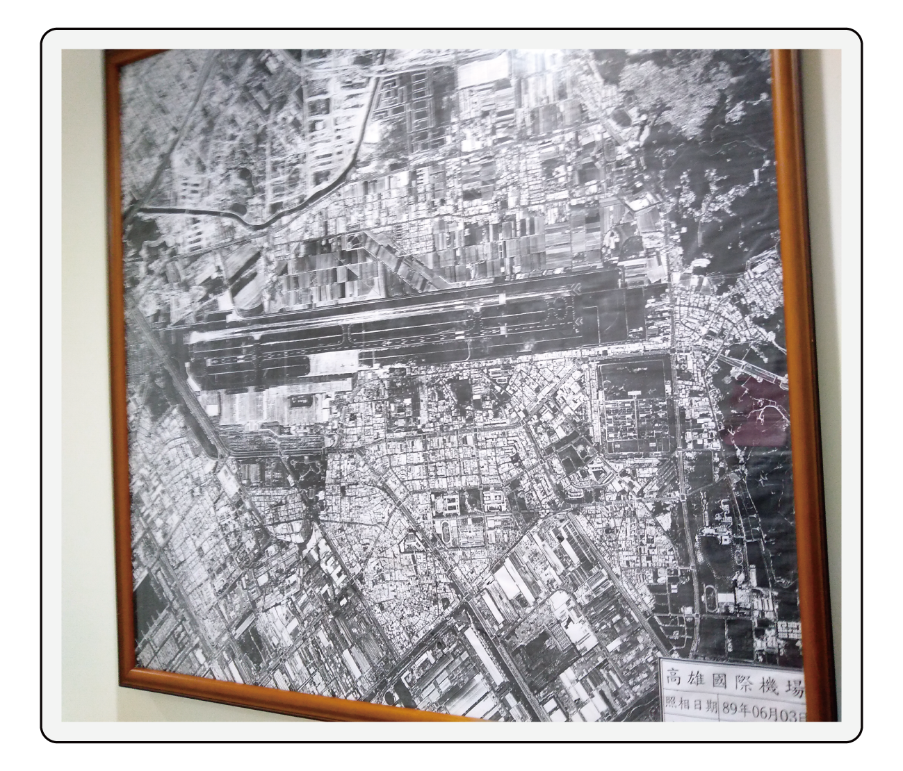 圖片說明：檔案庫房入口牆面銜掛     高雄機場基地圖檔及當時空拍圖，     隱喻其庫房有其重要檔案之氛圍